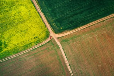 Aerial photo showing combine harvester on a farm track at intersection of four fields